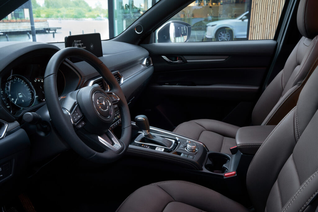 Vue de l'intérieur de l'habitacle du CX-5, avec focus sur le volant et la console centrale.