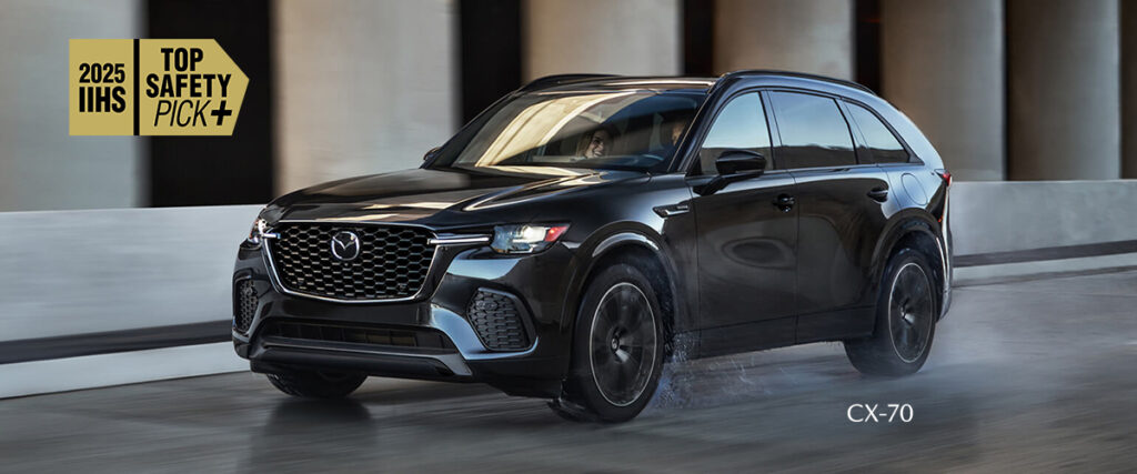 2025 Mazda CX-70 black SUV driving under an overpass, recognized as an IIHS Top Safety Pick+ for optimal safety